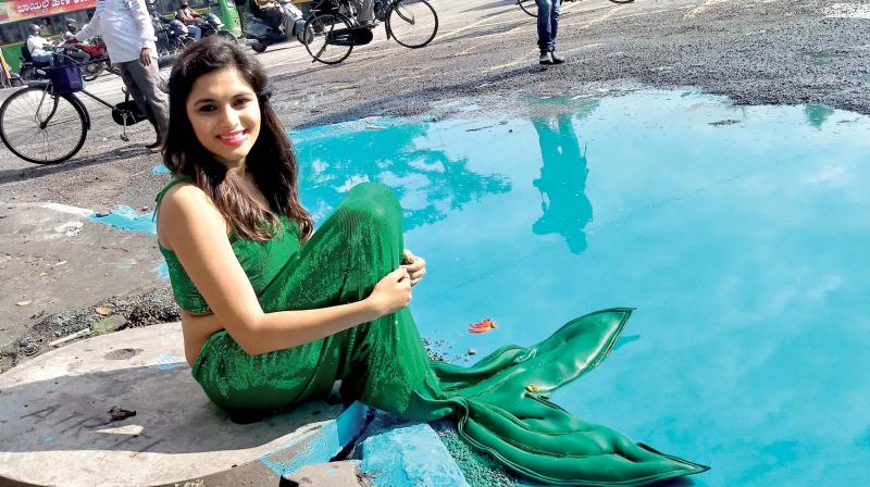 Actress Sonu Gowda dressed as a mermaid poses next to a huge pothole.
