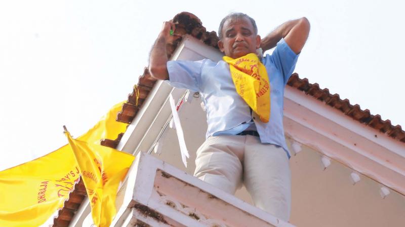 A member of the Jacobite church climbs atop the Piravom church threatening to commit suicide.(Photo: DC)