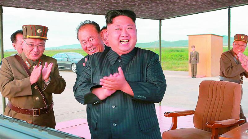 North Korean leader Kim Jong Un celebrates the test launch of an intermediate range missile (right) at an undisclosed location in North Korea. (Photo: AP)