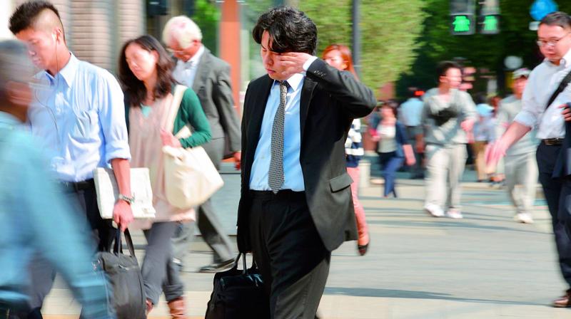 A Japanese businessman, called salaryman, rubbing his eyes as he heads to work. (Photo: AFP)