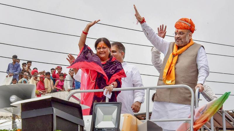 BJP President Amit Shah with Rajasthan Chief Minister Vasundhara Raje wave at their supporters during a public meeting