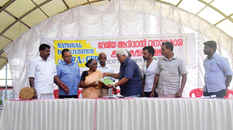 Dr Pradeep Prabhu, prominent activist of tribal rights, releases a status report of implementation of Forest Rights Act by handing over copy to Padikkappu Ooru chieftain Udaya Kali at a meeting held in Kochi.