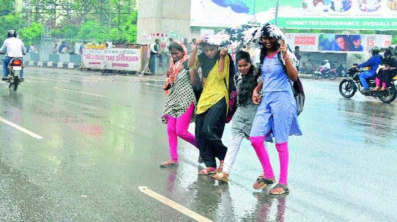 Women try to cover from rain at Nampally on Friday. 	(Image: P. Surendra)