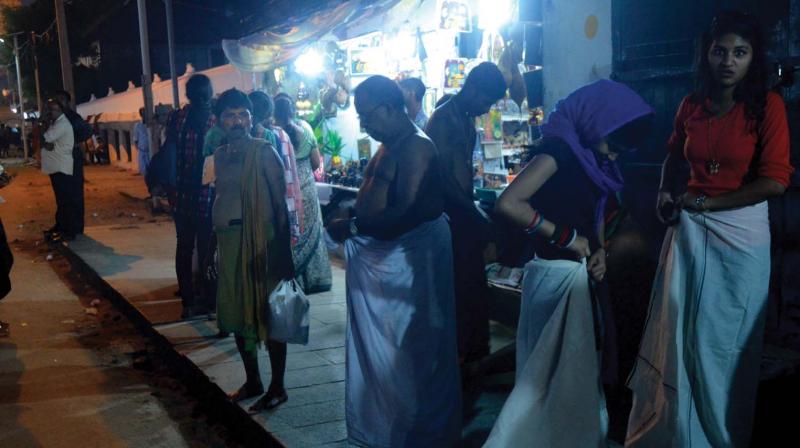 Women, unaware of the lifting of churidar ban, wrap themselves with dhoti at Padmanabha Swamy temple on Tuesday night. (Photo: DC)