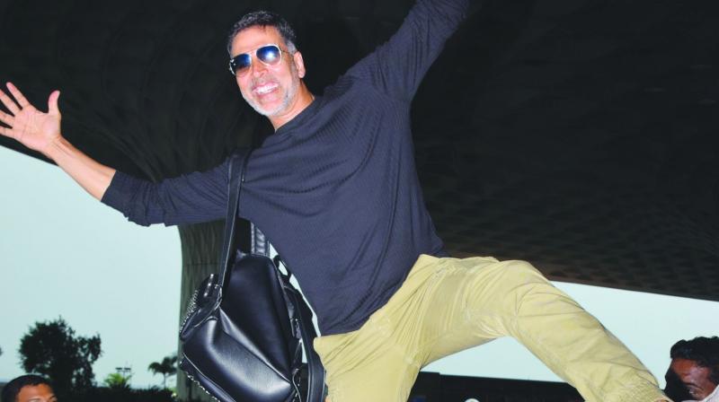 With a little help from his bodyguard, Akshay jumped up on one of the short pillars outside the airport and balanced himself atop it on one leg.