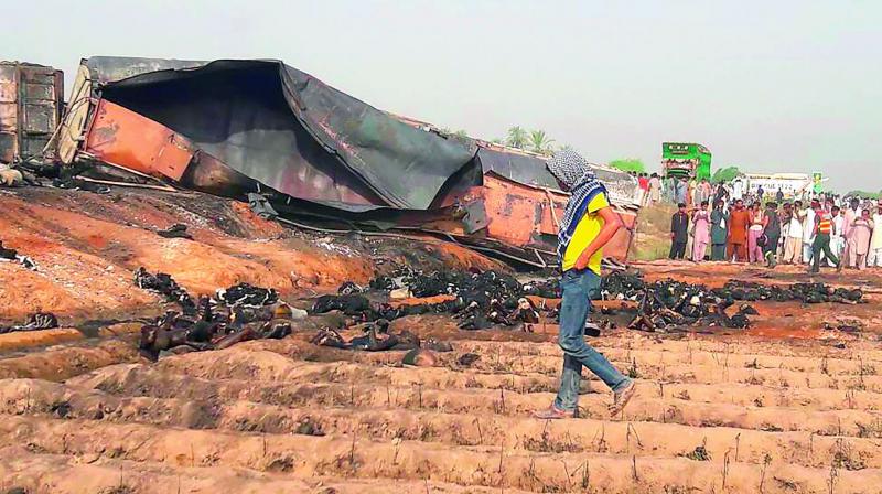 Charred bodies lie beside the burnt trailer of the oil tanker that caught fire following an accident on a highway near the town of Ahmedpur East, some 670 km from Islamabad on Sunday. (Photo: AFP)
