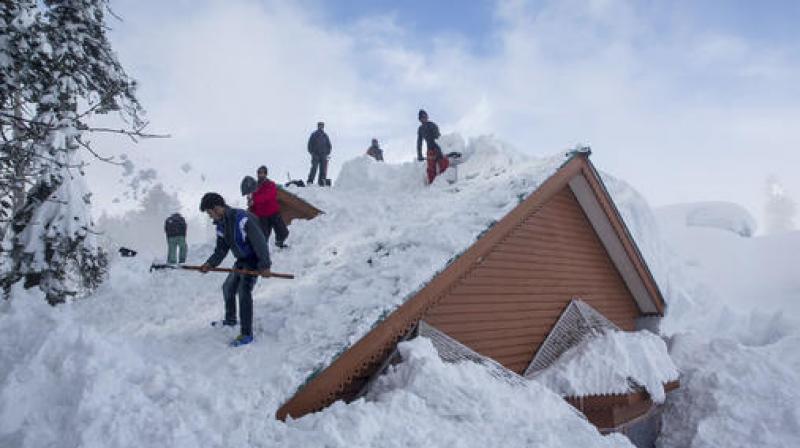 Kashmiris remove roof of a house in Gulmarg, about 55 kilometres northwest of Srinagar, following several avalanches in the area. (Photo: AP)