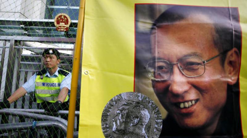 A police officer stands guard beside a picture of jailed Chinese dissident Liu Xiaobo outside the Chinese government liaison office in Hong Kong. (Photo: AP)