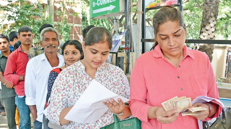 Women fill forms and count the money while standing in a queue to exchange the demonetised 500 and 1,000 notes at a bank in the city on Monday. (Photo: DC)