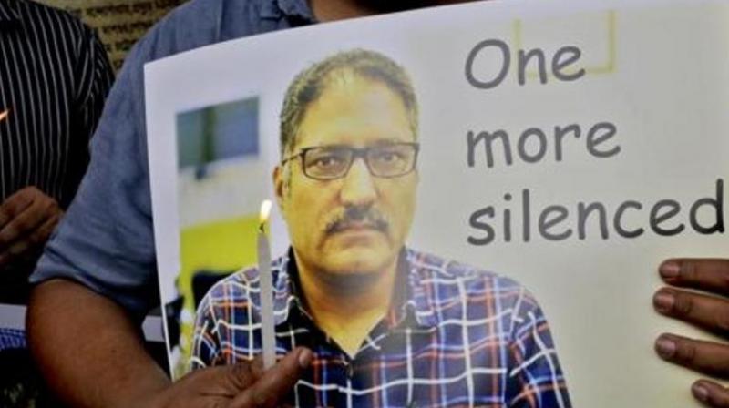 A journalist participates in a silent protest against the brutal killing of a senior Kashmiri journalist Shujaat Bukhari, portrait seen, in Kolkata on June 15, 2018. (Photo: AP)