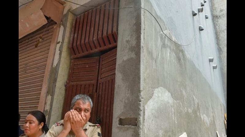 Policemen stand near the wall where 11 pipes seen protruding out of the house, where 11 members of the same family allegedly committed suicide, at Burari, in New Delhi. (Photo: PTI)