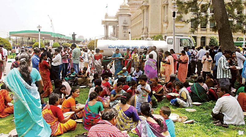 A file photo of people having lunch on the premises of Vidhana Soudha during distribution of free ration to BPL card holders under Anna Bhagya scheme, in Bengaluru.  (Photo:KPN)