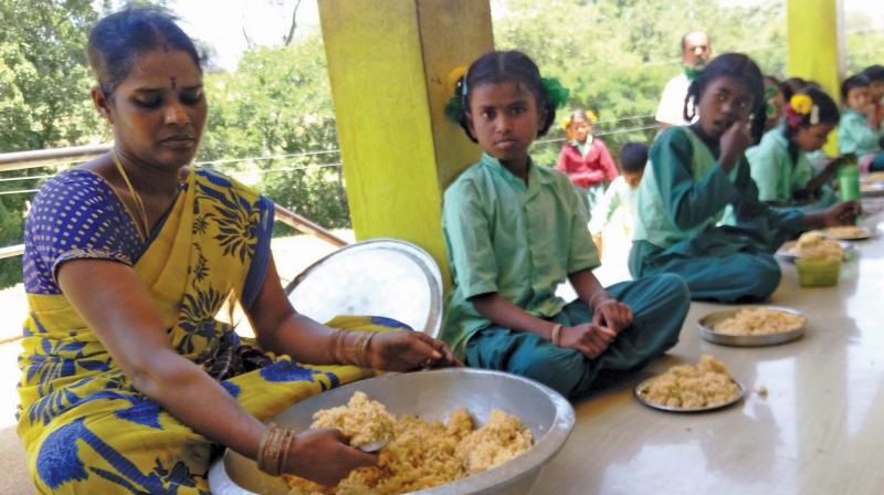 Noon meal cook Mageshwari gives food to the  children.	(Image: DC)