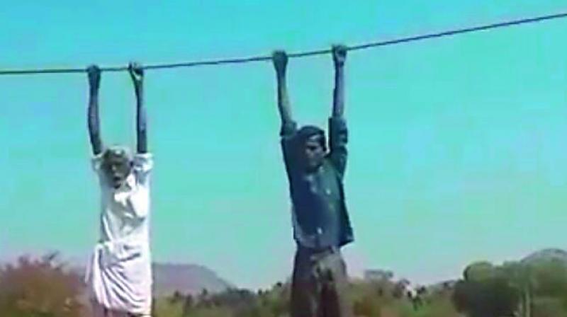 A farmer and his son protest against the laying of high-tension wires through their patch of agricultural land near Melavoy in Anantapur district on Sunday.