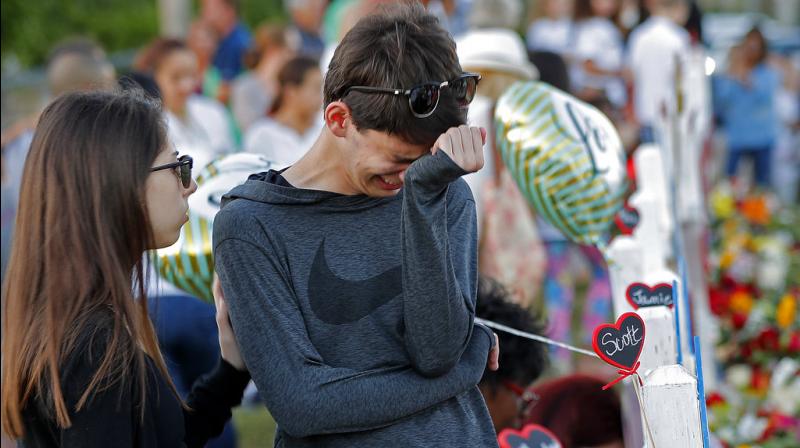 Daniel Bishop, 16, a student at Marjory Stoneman Douglas High School, cries at a makeshift memorial outside the school, in Parkland, Fla., Sunday, Feb. 18, 2018. Nikolas Cruz, a 19-year-old who had been expelled from the school, is being held without bail in the Broward County Jail, accused of 17 counts of first-degree murder. (Photo: AP)