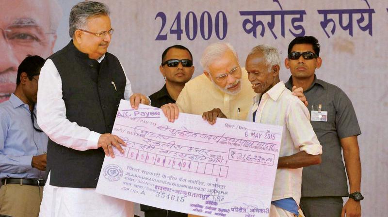 Prime Minister Narendra Modi and Chhattisgarh Chief Minister Raman Singh (left) present bonus of a scheme to a farmer at a public meeting in Dantewada, Chhattisgarh. (Photo: PTI)