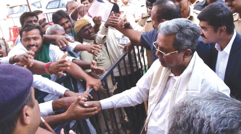 Chief Minister Siddaramaiah with farmers  at Kamadoda in Ranibennur taluk of Haveri district on Sunday. (Photo: KPN)