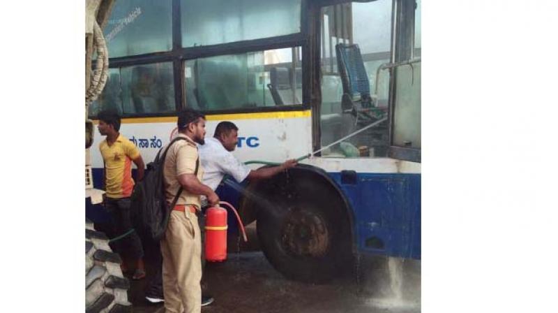 Staff and nearby residents douse the fire in a BMTC bus near Navayuga tollgate, in Nelaman- gala on Monday  (Image DC)