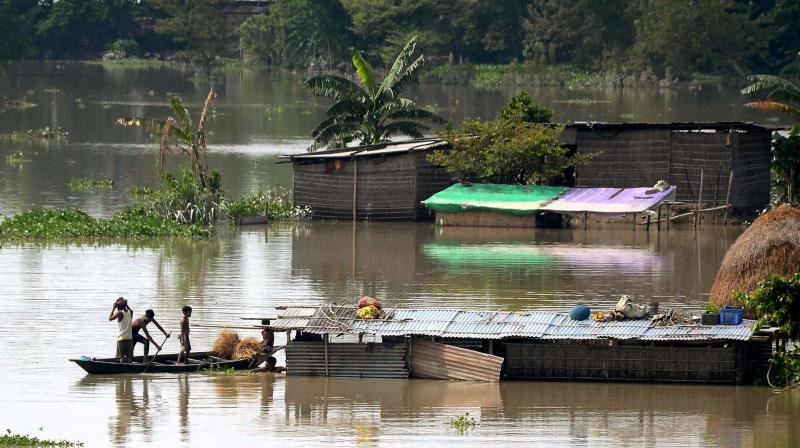 Flood-affected villagers commute to safe place using a boat in Morigaon district of Assam on Thursday. (Photo: PTI)
