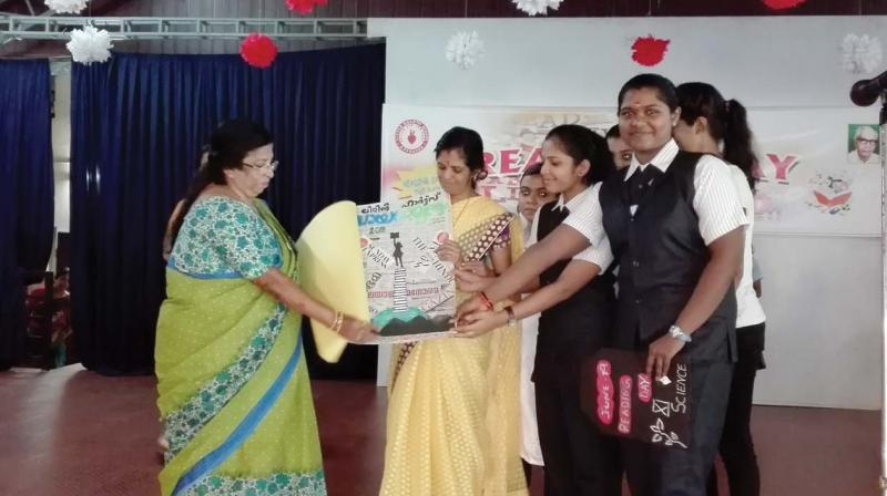 First teacher Nancy Sebastian receives a magazine prepared by the students on occasion of Reading Day at Little Hearts School, North Paravoor.
