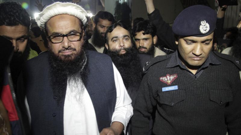 officer escorts Hafiz Saeed Chief of Pakistans religious group Jamaat-ud-Dawa outside partys headquarters in Lahore, Pakistan. (Photo: AP)