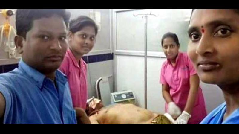 A ward boy is seen taking a selfie from his mobile phone with the actor-politicians body in the backdrop. A ward girl and two nurses are also looking into the camera. (Screengrab | Twitter)