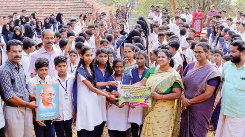 Thamarasserry grama panchayat president K. Saraswathi felicitates the students of VIII G division of GVHSS Thamarasserry for dumping plastic pen at the school. 	(Photo: DC)
