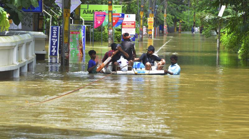 People move past a flooded area in Thrissur, Kerala. Rescuers used helicopters and boats on Friday to evacuate thousands of people stranded on their rooftops following unprecedented flooding in Kerala. (Photo: AP)