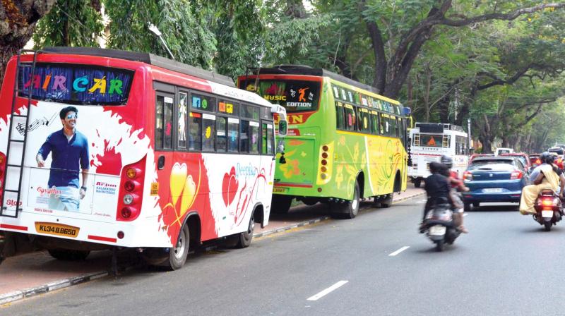 Tourist buses parked on the polymer coated interlock tiled footpath in front of the busy Museum road in Thiruvananthapuram.