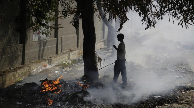 A boy stands next to burning garbage on the outskirts of New Delh on Tuesday. (Photo: PTI)