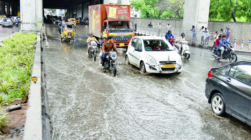 Commuters wade through the waterlogged road under the Ameerpet Metro station.  (Photo:S. Surender Reddy)