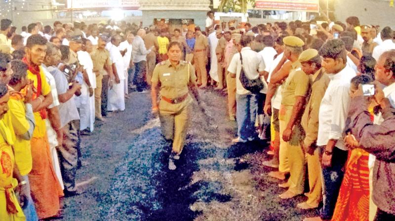 A woman police officer walks on the red hot coal bed at the temple. (Photo: DC)