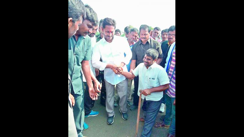Jagan Mohan Reddy meets a challenged person at Four Road Circle in Allagadda on Wednesday.