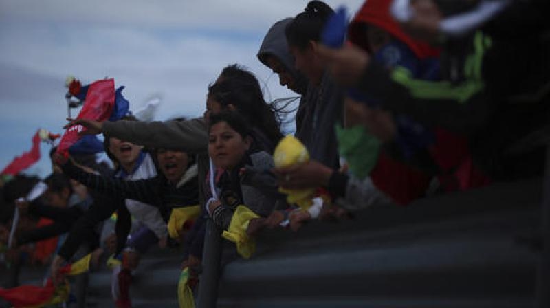 Young people hold colored flags reading Peace as they form a symbolic human wall along the Rio Grande, which marks the border between Mexico and the US in Ciudad Juarez. (Photo: AP)