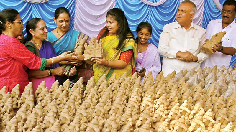 Former Minister Ramalinga Reddy (extreme right) and MLA Sowmya Reddy (centre) distribute free Ganesha idols in Jayanagar to create awareness about using clay Ganeshas on Tuesday (Image DC)