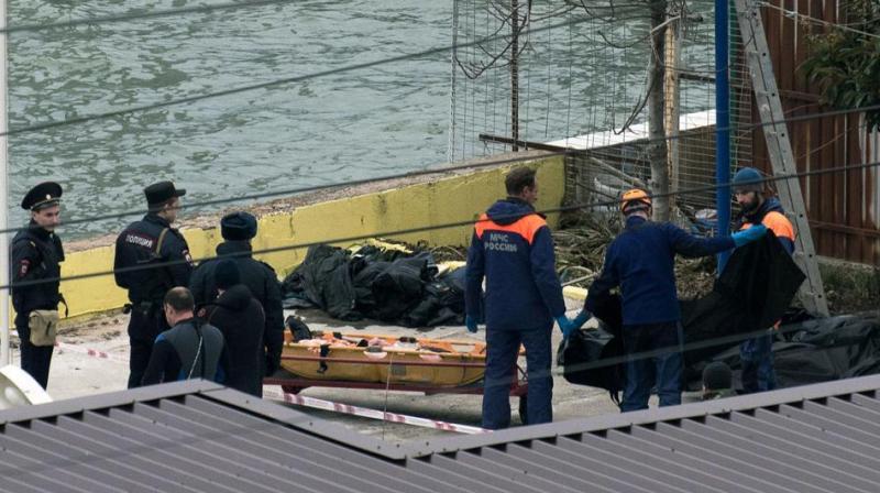 Russian policemen and rescuers stand near a stretcher with a body recovered after a Russian military plane crashed in the Black Sea, on a pier outside Sochi. (Photo: AFP)