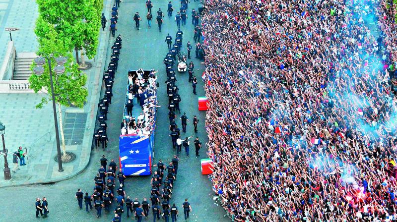 Fans greet the France national football team players as they celebrate on the roof of a bus while they parade down the Champs-Elysee avenue in Paris. (Photo: AFP)