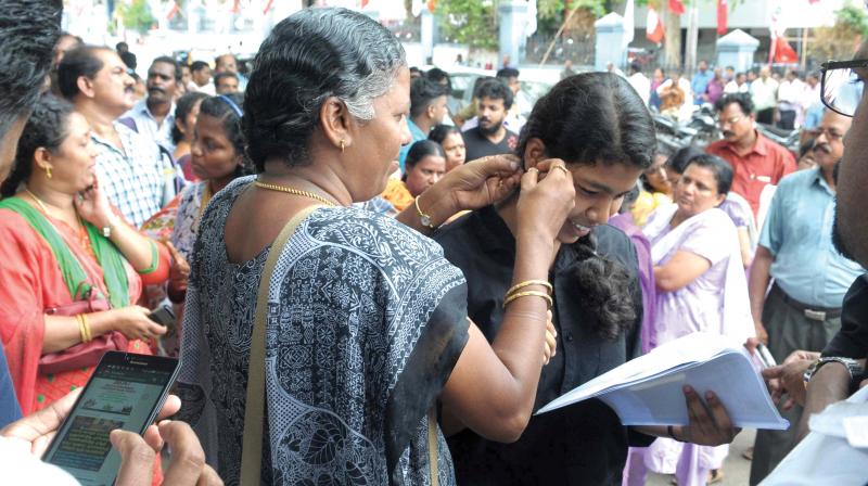 A woman removes her daughters earrings before the NEET examinations at Arya Central school in Thiruvananthapuram on Sunday. 	(Photo: DC FILE)