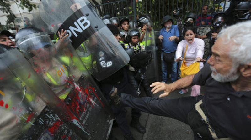 An anti-government protester kicks at riot police blocking a march of elders against President Nicolas Maduro in Caracas, Venezuela. (Photo: AP)