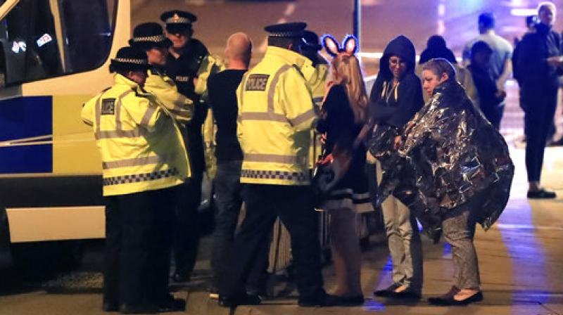 Emergency services personnel speak to people outside Manchester Arena after reports of an explosion at the venue during an Ariana Grande concert in Manchester, England. (Photo: AP)