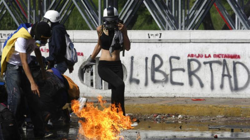 Protesters take cover from fire thrown by riot police during a march towards the Ombudsmans Office in protest of President Nicolas Maduro in Caracas, Venezuela. (Photo: AP)