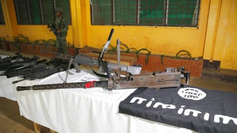 A Philippine Marine guards communication equipment, high-powered firearms, including a 50-caliber machinegun, ammunitions, uniforms, and black ISIS-style flags Tuesday in Marawi city southern Philippines.