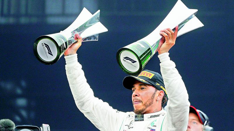 Mercedes driver Lewis Hamilton of Britain raises trophies after winning the Brazilian Formula One Grand Prix at the Interlagos race track in Sao Paulo, Brazil, on Sunday. (Photo:  AP)