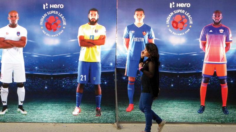 A girl walks past the horadings put up at the Jawaharlal Nehru Stadium on the eve of the ISL final. (Photo: Vinod Karimatt)