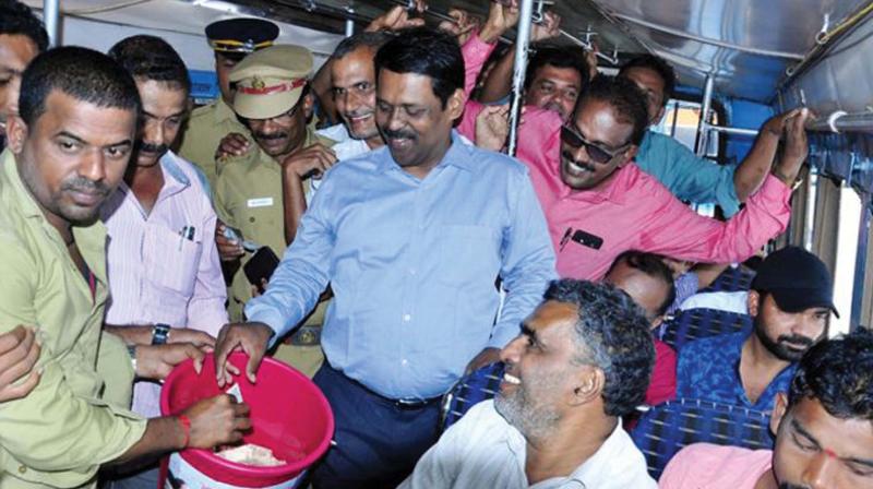 Kasargod district collector Dr Sajith Babu puts money in the bucket in a private bus which has been part of the CMDRF fund collection drive in Kasargod on Thursday