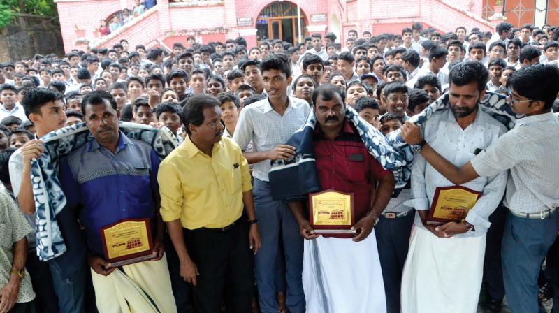 The students of Government Model High School honou  Paniyadima, Freddie, and Jiller, the fishermen from Vizhinjam who rescued several lives from the recent flood  in Pathanamthitta, at a function in Thiruvananthapuram on Thursday. Headmaster Suresh Babu looks on