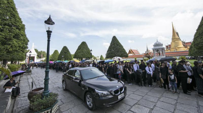 A car drives past Thai mourners lined up for a bathing ceremony for Thai King Bhumibol Adulyadej at the Grand Palace in Bangkok, Thailand, Friday, October 14, 2016. (Photo: AFP)