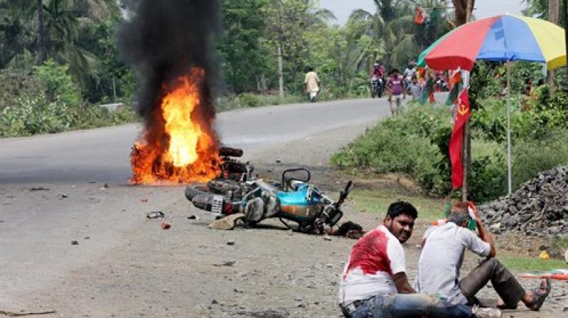 People injured in poll violence sit by the side of a road as a vehicle is set on fire by locals during Panchayat polls, in Nadia district of West Bengal on Monday. (Photo: PTI)