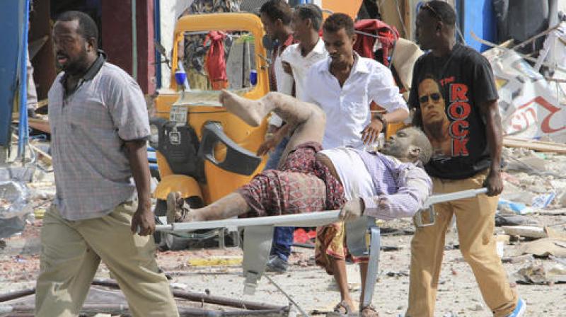 Somali men carry a civilian who was wounded in a suicide car bomb attack on a hotel in Mogadishu. (Photo: AP)