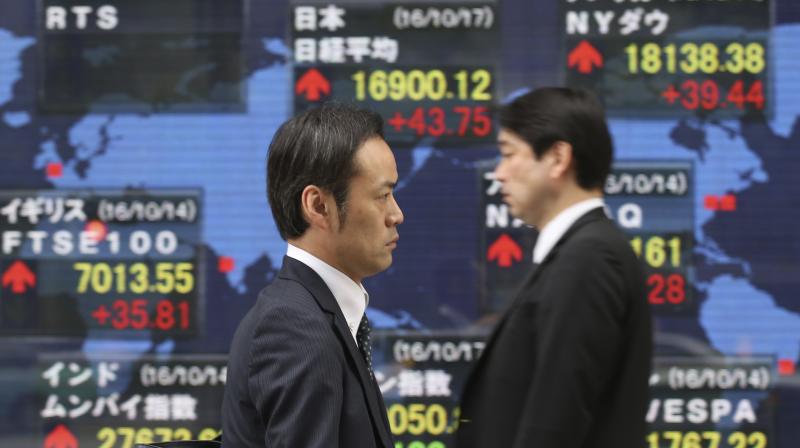 People walk by an electronic stock board of a securities firm in Tokyo. (Photo:AP)